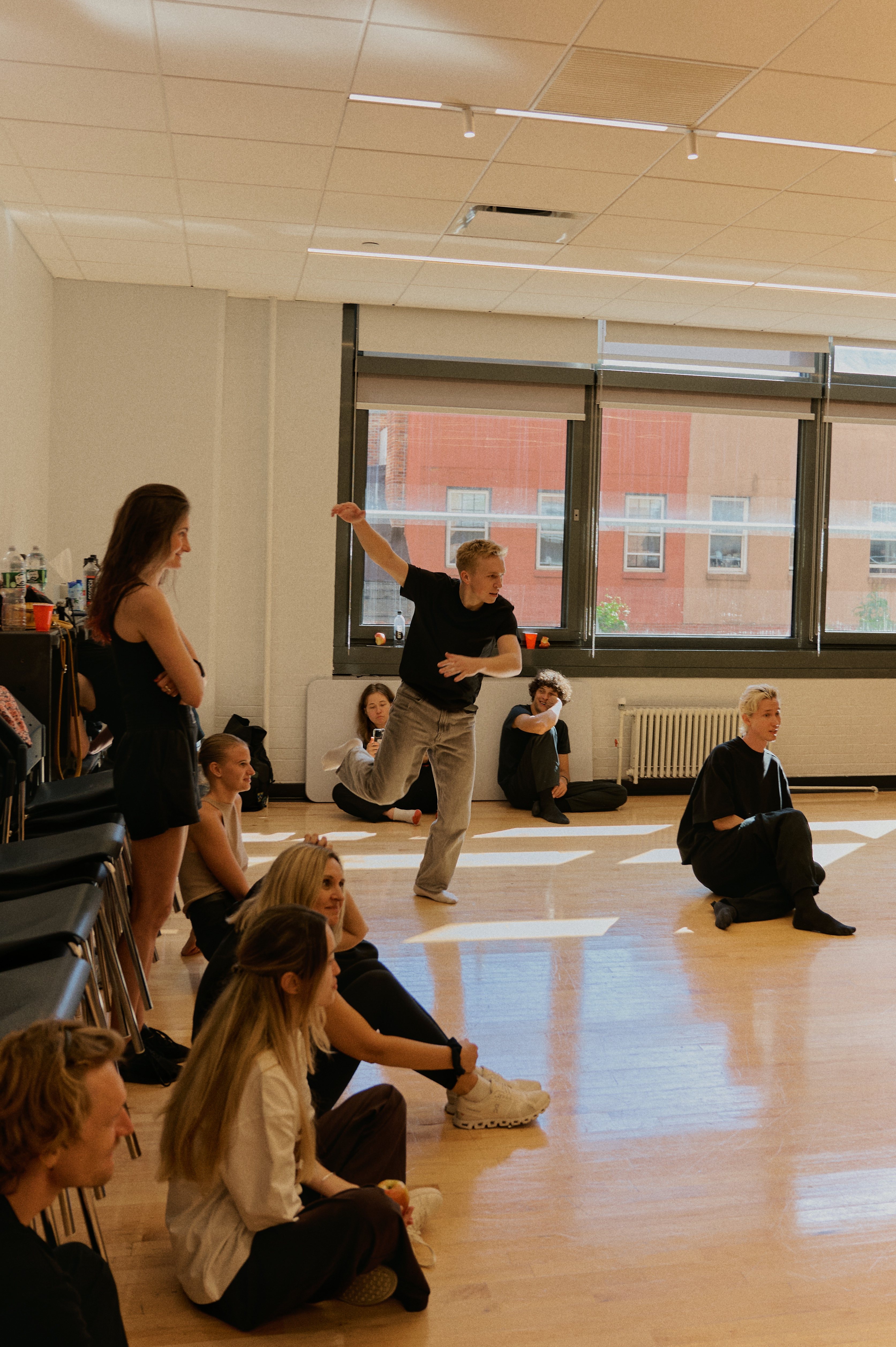 Workshop instructor demonstrating to seated participants by large windows